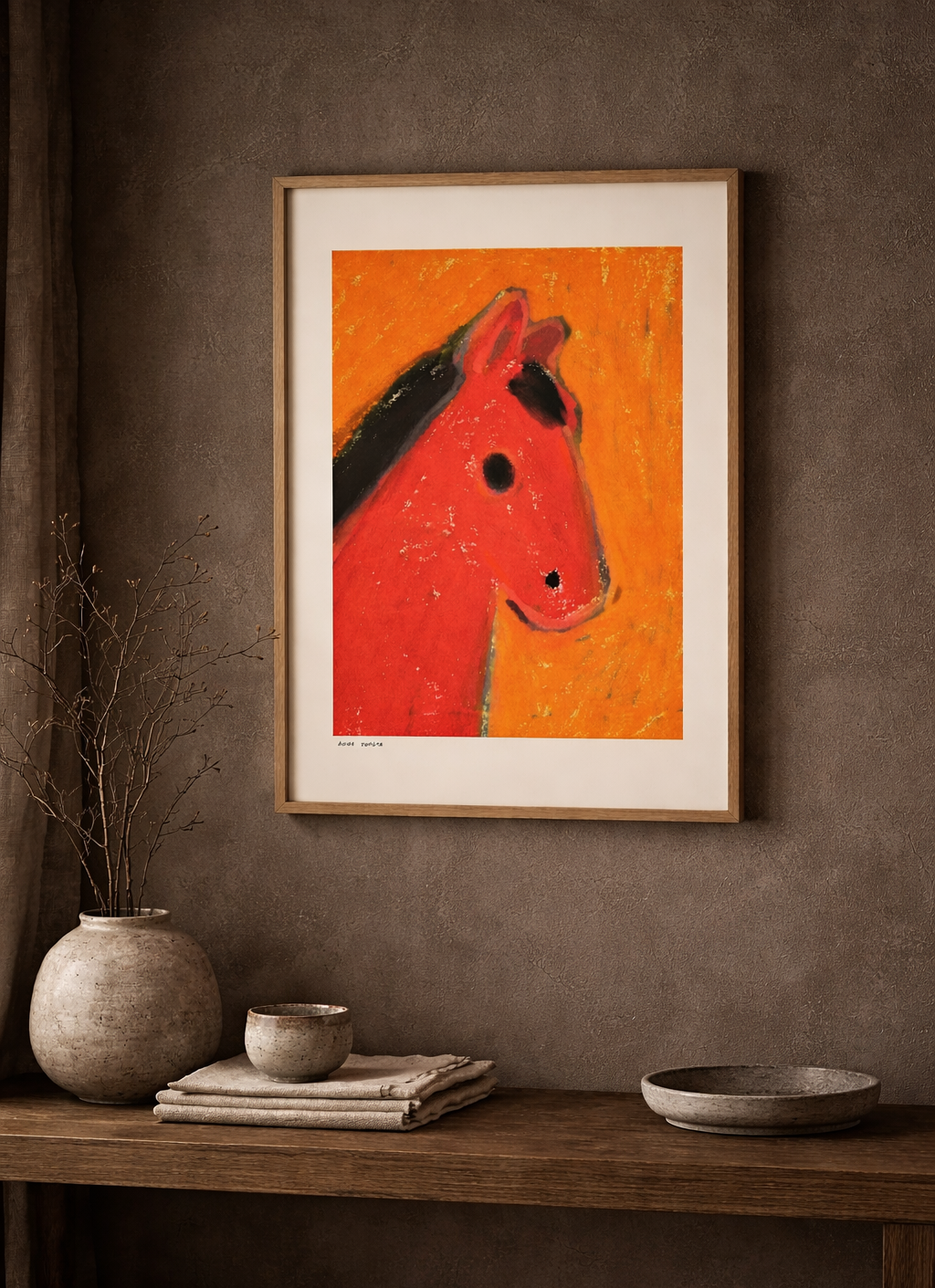 Framed artwork of a red horse head on an orange background, displayed on a wooden shelf against a brown wall.