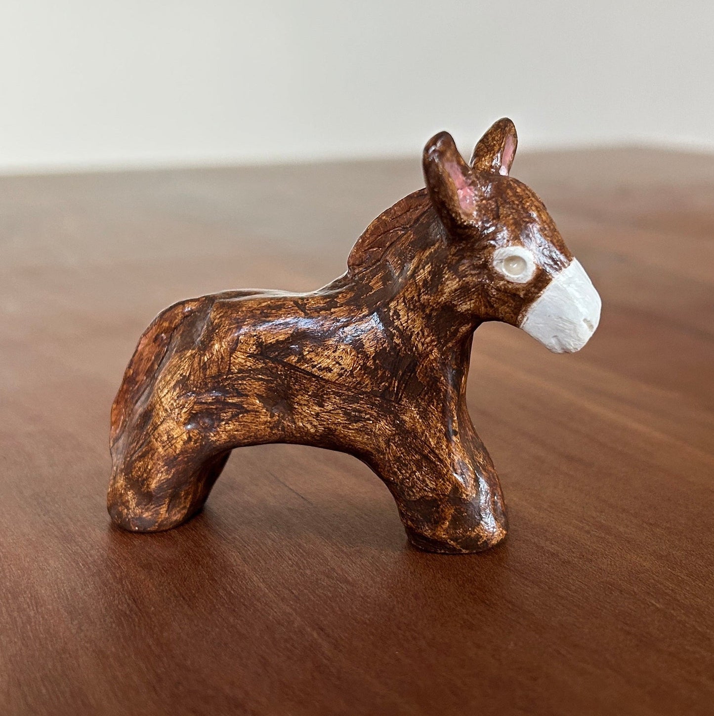 Small brown ceramic donkey figurine on a wooden surface