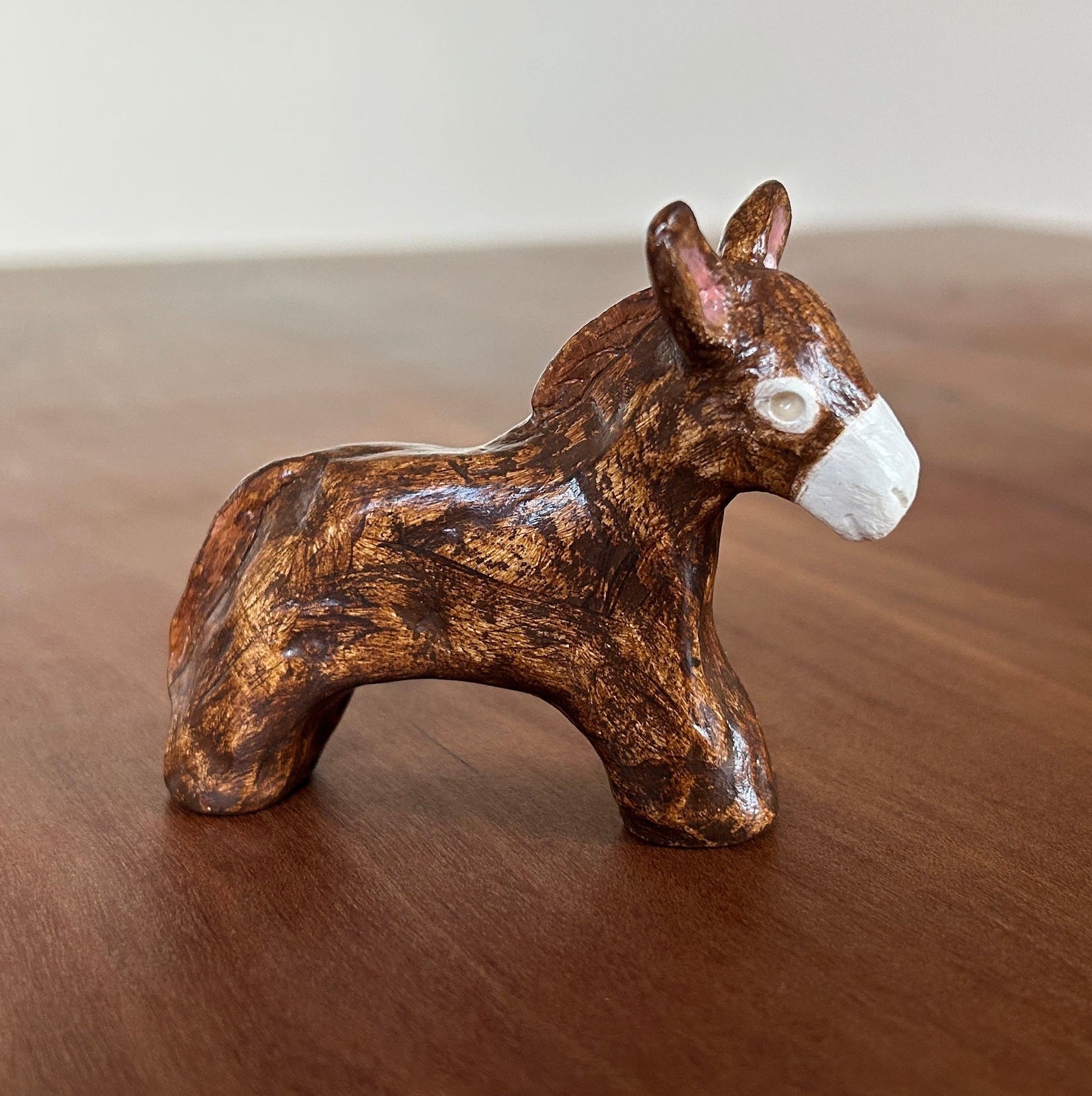 Small brown ceramic donkey figurine on a wooden surface