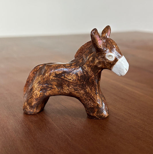 Small brown ceramic donkey figurine on a wooden surface