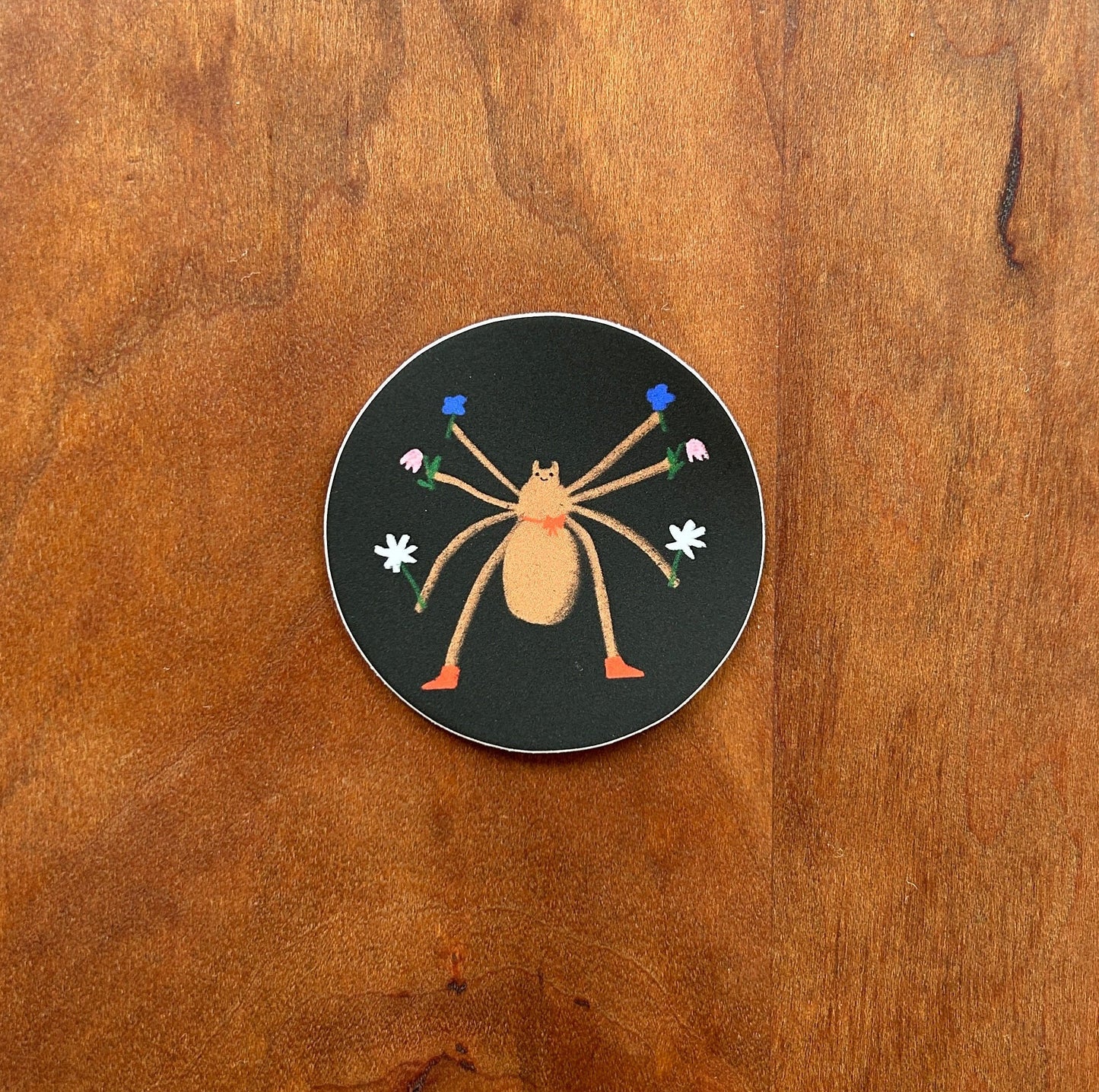 Circular sticker with a spider design on a wooden surface
